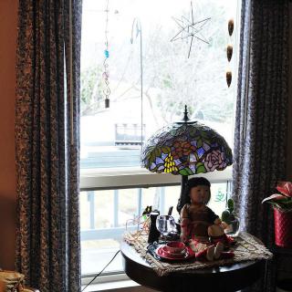 A cozy interior space features a decorative lamp and figurine on a table by the window.