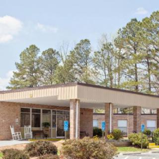 A small brick building with a covered entrance surrounded by trees.