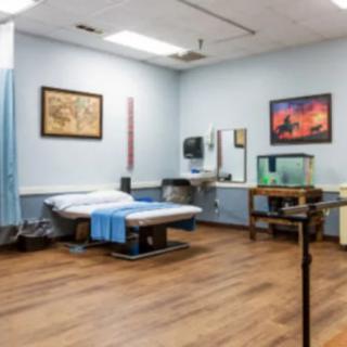 A clean and organized medical exam room with a treatment table and various equipment.