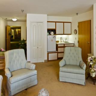 A cozy living area featuring two armchairs and a small kitchenette.