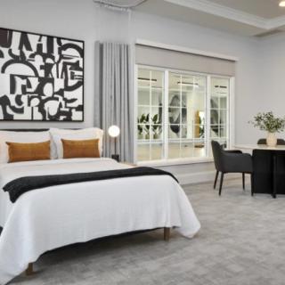 A modern bedroom with sleek furnishings and abstract artwork.