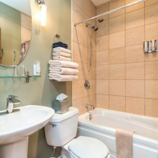 A clean and organized bathroom with a bathtub, sink, and neatly stacked towels.