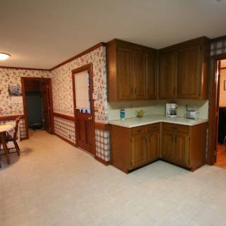 A spacious kitchen featuring wooden cabinets, vintage wallpaper, and a cozy dining area.