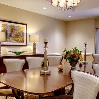 A well-decorated dining room featuring a wooden table, upholstered chairs, artwork on the wall, and a chandelier.