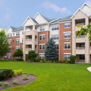 A multi-story apartment building with well-maintained landscaping and a spacious lawn.