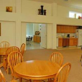 A spacious dining area with wooden tables and chairs, adjacent to a kitchen.