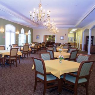 A spacious dining room with elegantly set tables and chandeliers.