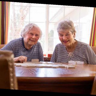 Two seniors enjoying a game together at a table.