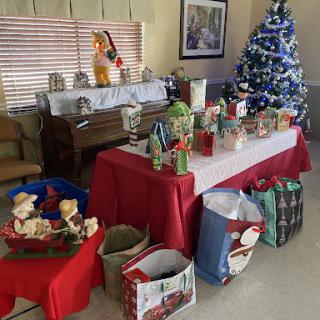 A cozy holiday setup featuring a decorated Christmas tree and a table full of festive decorations and gifts.
