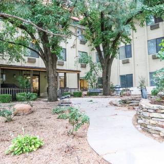 A landscaped outdoor area with a pathway and surrounding trees in front of a building.