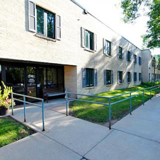 A modern building with a ramp leading to the entrance, surrounded by green grass and trees.