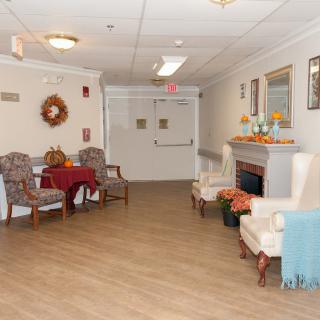 A cozy lobby area with chairs, a table, and a decorative fireplace.