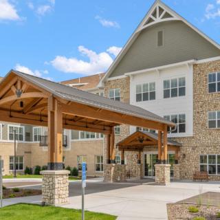 A modern residential building with a stone facade and a covered entrance.
