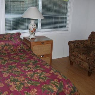 A cozy bedroom with floral bedding and a patterned armchair.