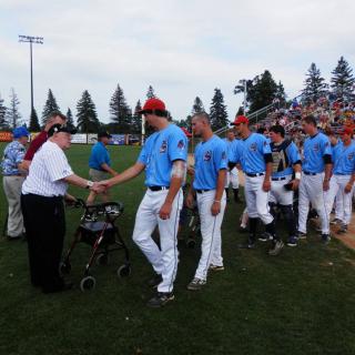 A baseball team in blue uniforms shakes hands on the field.