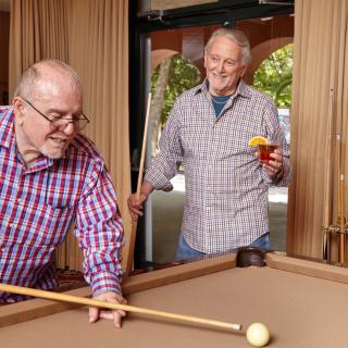 Two senior men enjoying a game of pool together.