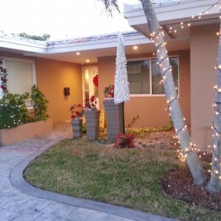 A welcoming house entrance with decorative lights and a garden pathway.