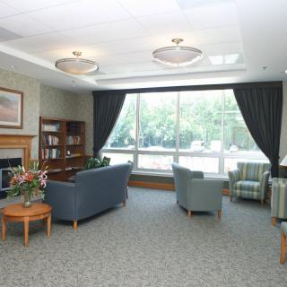 A cozy living room with comfortable seating, a bookshelf, and large windows letting in natural light.