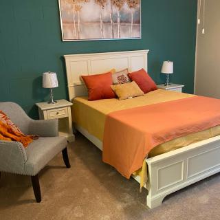 A cozy bedroom with vibrant orange accents and classic white furniture.