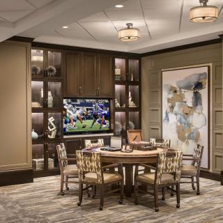 A luxurious room with a dining table, modern artwork, and a television displaying a sports game.