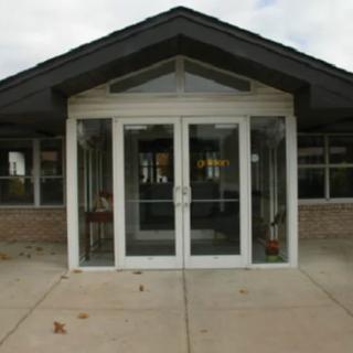 A building entrance with glass doors and brick walls.