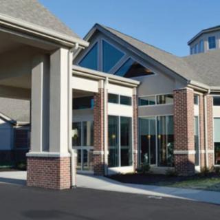 A modern building with large glass windows and brick accents at the entrance.