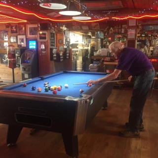 Person playing billiards in a cozy bar setting.