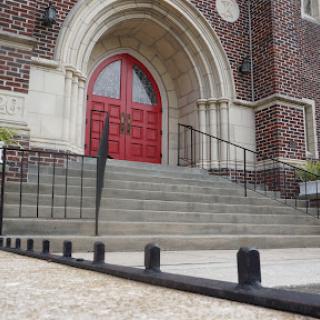 The entrance of a church featuring striking red doors and stone steps.