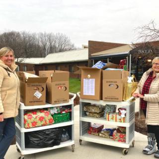 Two volunteers stand outdoors with carts full of donation boxes, contributing to a community charity effort.