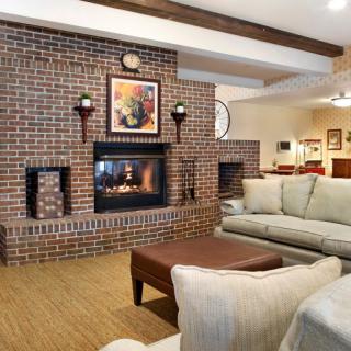A cozy living room with a brick wall and a warm fireplace, featuring comfortable couches and a coffee table.