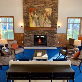 A cozy living room with a stone fireplace, modern furniture, and a large abstract painting above the mantel.