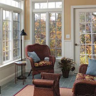 Cozy sunroom with a view of autumn foliage through large windows.