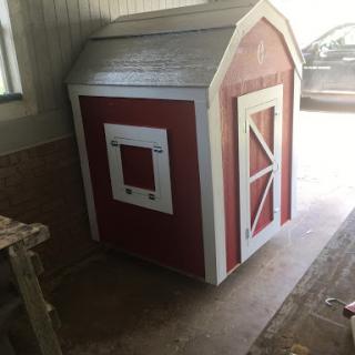 A cozy red dog house with a classic design, perfect for providing shelter to your furry friends.