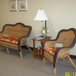 A cozy waiting area with wicker furniture and a lamp on a small table.
