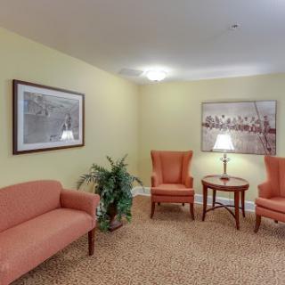 A cozy waiting area featuring orange seating, a small table, and decorative wall art.