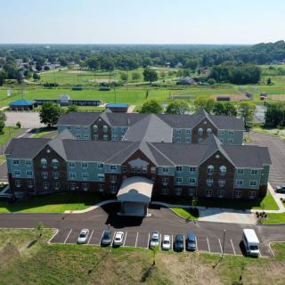 An aerial view of a large building with a parking lot in a landscaped area.