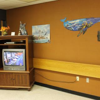 A cozy living room setting featuring a television and colorful wall art.