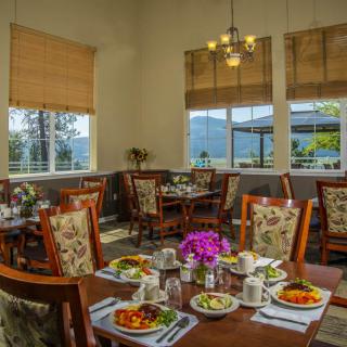 A cozy restaurant dining room with elegantly set tables and a view of the outside.