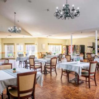 A spacious and elegantly designed dining room with multiple tables and chairs, featuring chandeliers.