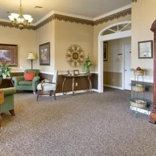 A cozy living room with comfortable armchairs, decorative art pieces, and warm lighting.