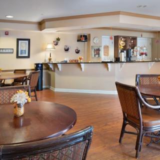 A cozy dining area with wooden tables and chairs, featuring a bar counter in the background.