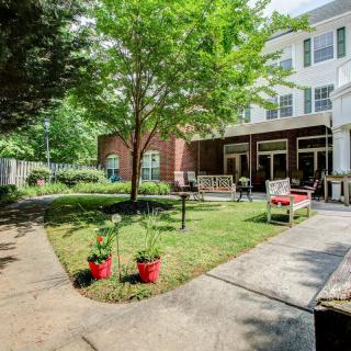 A peaceful garden area with seating and a path leading to a building.