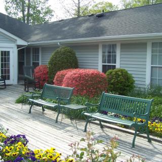 A serene garden with benches and colorful shrubbery in front of a house.
