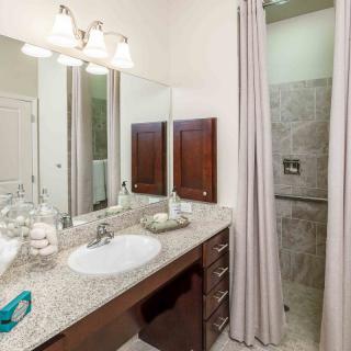 A modern bathroom with a sink, mirror, and shower area.
