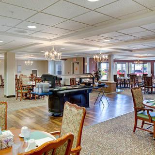 A spacious dining area featuring elegant chandeliers, tables with chairs, and a warm interior design.