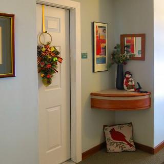 A cozy hallway with a decorated door, wall art, and a small shelf with decorative items.
