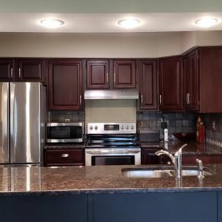 A modern kitchen with stainless steel appliances and dark wooden cabinets.