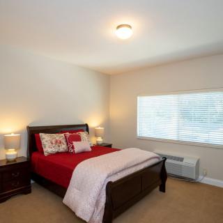Bright and cozy bedroom with red bedding and matching nightstands.