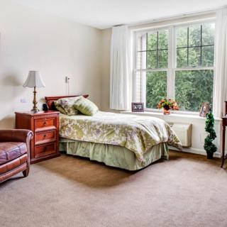 A cozy bedroom with a bed, armchair, and large window.