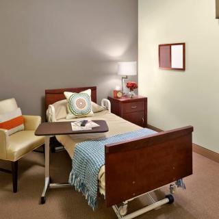 A cozy hospital room with a bed, chair, and bedside table.